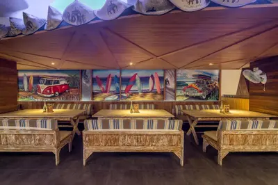 a restaurant with wooden tables and paintings on the walls at Bliss Surfer Hotel Legian in Legian