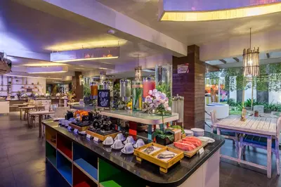 a restaurant with a counter with food on it at Bliss Surfer Hotel Legian in Legian