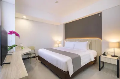 a hotel room with a large bed and a desk at Royal Regantris Kuta in Kuta