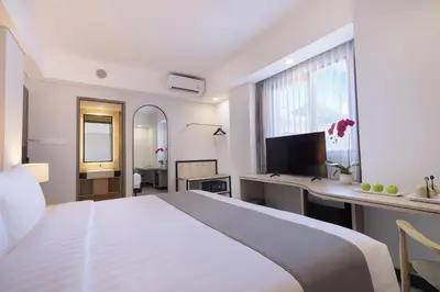 a white bedroom with a large bed and a desk at Royal Regantris Kuta in Kuta