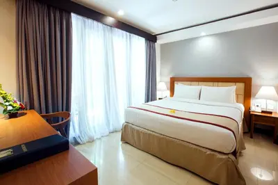 a hotel room with a large bed and a window at Royal Regantris Kuta in Kuta