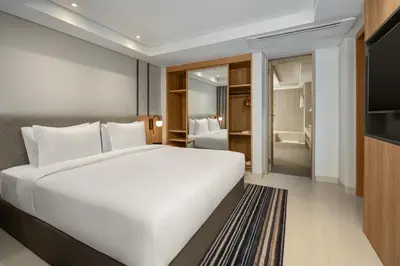 a bedroom with a large white bed and a bathroom at Holiday Inn Express Bali Sunset Road by IHG in Kuta