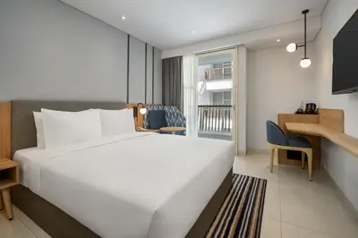 a bedroom with a large white bed and a desk at Holiday Inn Express Bali Sunset Road by IHG in Kuta