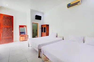 two beds in a white room with a door at Collection O Sanur Near Bali Exotic Marine Park in Sanur