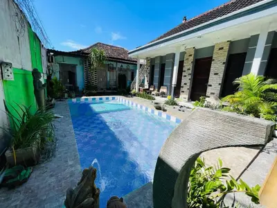 a swimming pool in front of a house with a chair at Collection O Sanur Near Bali Exotic Marine Park in Sanur