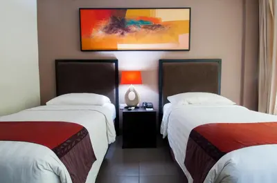 a hotel room with two beds and a picture on the wall at 100 Sunset Kuta Hotel & Ballroom in Kuta
