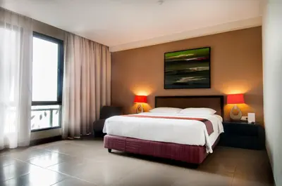 a hotel room with a bed and a large window at 100 Sunset Kuta Hotel & Ballroom in Kuta