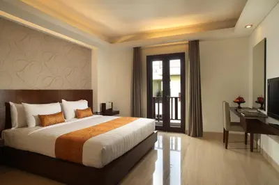a bedroom with a bed and a desk and a television at d'primahotel Seminyak in Seminyak