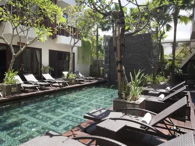 a swimming pool with lounge chairs in a courtyard at d'primahotel Seminyak in Seminyak