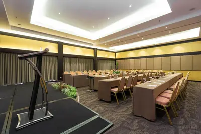 a conference room with tables and chairs and a microphone at Quest Hotel Kuta by ASTON in Kuta
