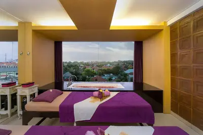 a bedroom with a purple bed and a large window at Quest Hotel Kuta by ASTON in Kuta