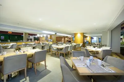 a dining room with tables and chairs and a restaurant at Quest Hotel Kuta by ASTON in Kuta