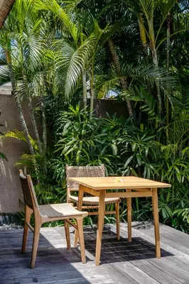 a wooden table and two chairs sitting next to a table and a bench at Space Villas Bali in Seminyak