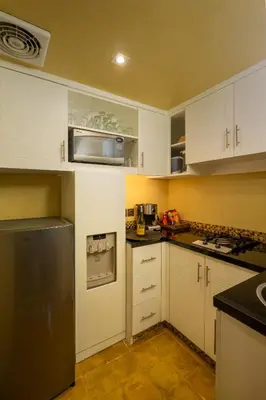 a kitchen with white cabinets and a stainless steel refrigerator at Space Villas Bali in Seminyak