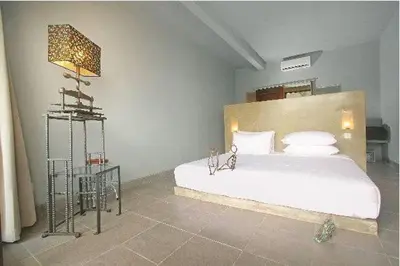 a bedroom with a white bed and a lamp at The Grey Boutique Inn in Legian