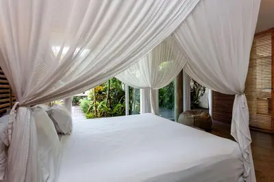 a bedroom with a white bed with white curtains at Villa C88 Seminyak in Seminyak