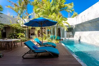 a pool with blue lounge chairs and an umbrella at Villa C88 Seminyak in Seminyak