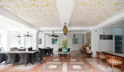 a living room with chairs and tables and a ceiling at Samsara Inn in Legian