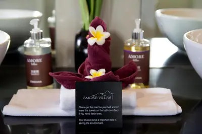 a towel dispenser with a flower on a table at Amore Villas in Canggu