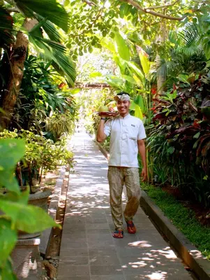 a man walking down a path in a garden at Amore Villas in Canggu