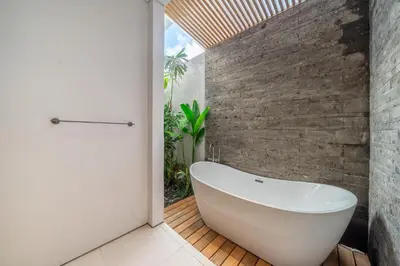 a bath tub in a bathroom with a brick wall at Villa Esa Seminyak in Seminyak