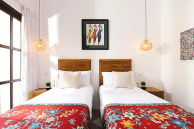 two beds in a room with white walls and windows at Villa Luma in Seminyak