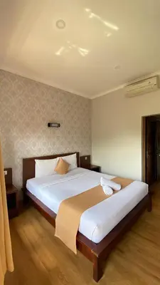 a bedroom with a large bed with white sheets at Surya Inn in Kuta