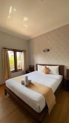 a large white bed in a bedroom with a window at Surya Inn in Kuta