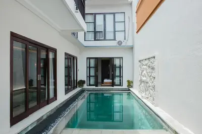 an indoor swimming pool in a house with windows at White Lotus Villas Seminyak in Seminyak