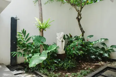 a garden with a statue in the middle of plants at White Lotus Villas Seminyak in Seminyak