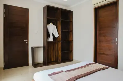 a bedroom with a bed and wooden doors and a closet at White Lotus Villas Seminyak in Seminyak