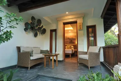 a porch of a house with chairs and a table at Puri Raja Hotel in Legian