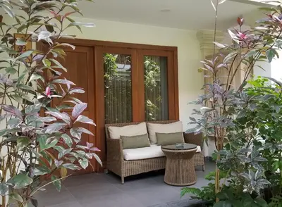 a wicker chair on a porch with plants at Puri Raja Hotel in Legian