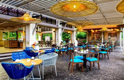 a restaurant with blue chairs and tables in a building at Puri Raja Hotel in Legian
