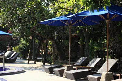 a group of chairs and a blue umbrella at Matahari Bungalow in Legian