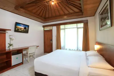 a bedroom with a large white bed and a desk at Matahari Bungalow in Legian