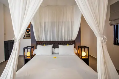 a bedroom with a bed with white curtains at Villa Surga in Seminyak