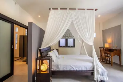 a bedroom with a bed with white curtains at Villa Surga in Seminyak