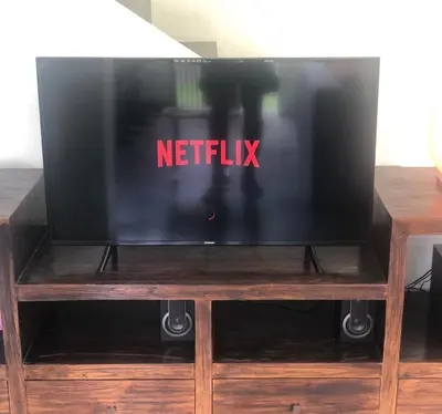 a tv on a wooden stand with a netflix sign on it at Villa Surga in Seminyak