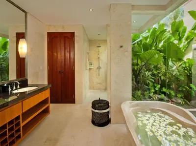a bathroom with a tub and a large plant at Villa Joss Seminyak by Nagisa Bali in Seminyak