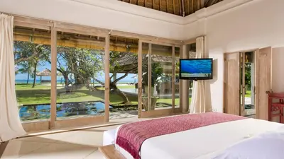 a bedroom with a bed and a large window at Villa Atas Ombak in Seminyak