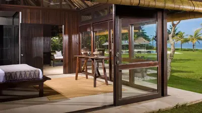 a room with glass doors and a bed and a table at Villa Atas Ombak in Seminyak