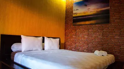 a bedroom with a bed with a brick wall at Leyeh Leyeh Homestay in Canggu