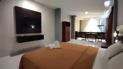 a hotel room with a bed and a flat screen tv at Gempita House Legian Bali in Legian