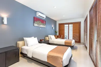 a hotel room with two beds and a table at Villa Hening Jimbaran in Jimbaran