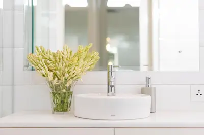 a bathroom sink with a vase of flowers and a mirror at Villa Neno in Seminyak
