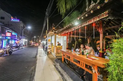 two people sitting at a table outside a restaurant at night at Legian Village Hotel - CHSE Certified in Legian