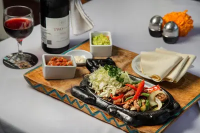 a plate of food on a table with a bottle of wine at Legian Village Hotel - CHSE Certified in Legian