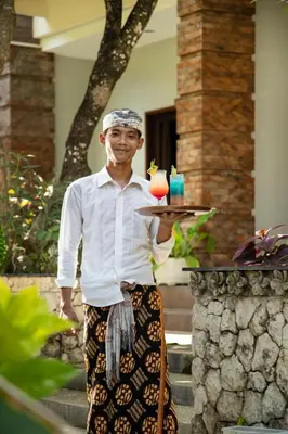 a man holding a tray with a drink on it at Legian Village Hotel - CHSE Certified in Legian