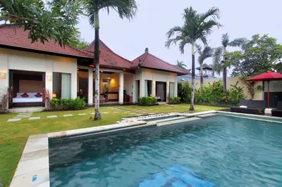 a villa with a swimming pool in front of a house at RC Villas and Spa Bali in Seminyak